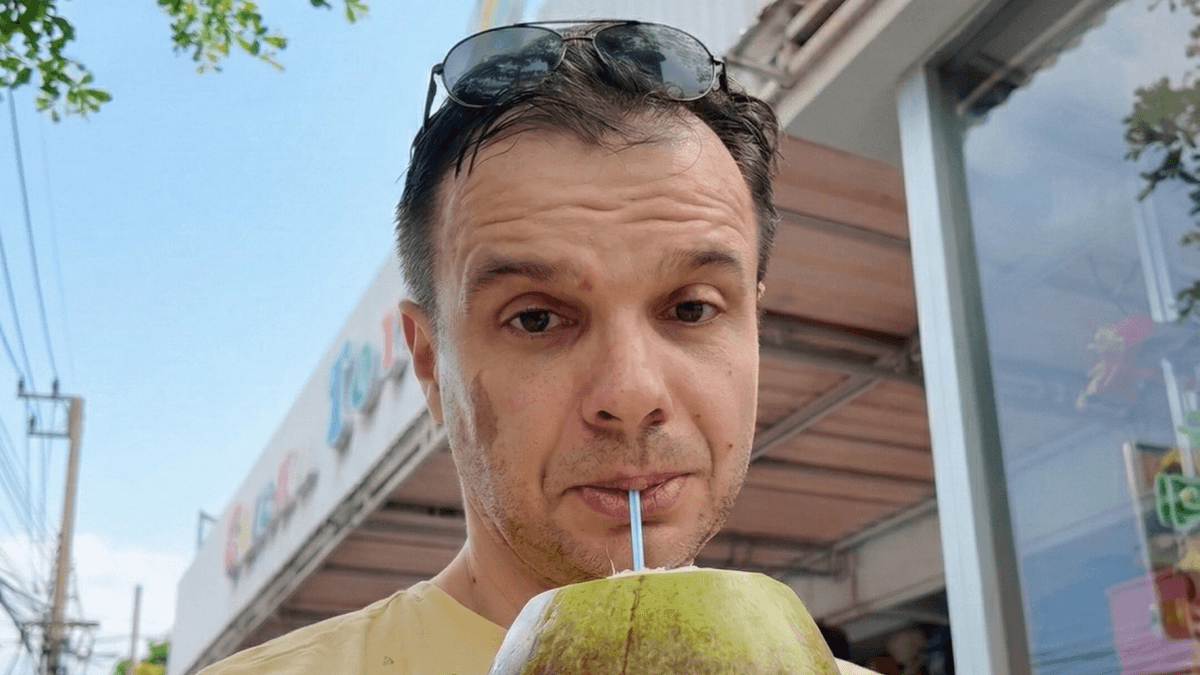 Krzysztof Musialik drinking a fresh coconut on a street in Bali